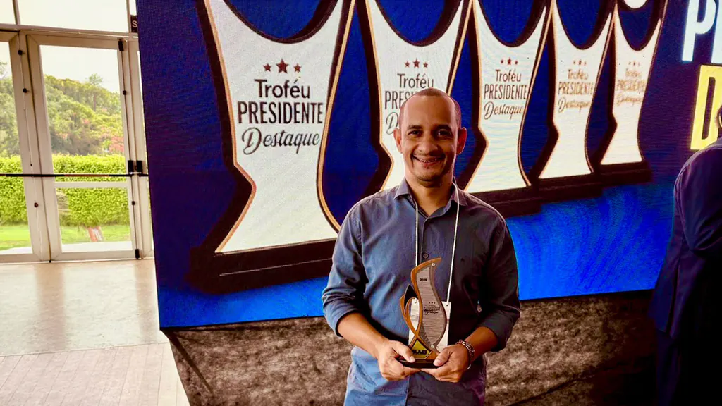 Pelézinho sorri segurando o Troféu Presidente Destaque 2025 diante do painel do prêmio, em Brasília