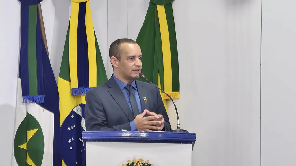 Pelézinho, presidente da Câmara, fala na tribuna da Câmara Municipal de São José do Rio Claro, com as bandeiras de Mato Grosso e do Brasil ao fundo