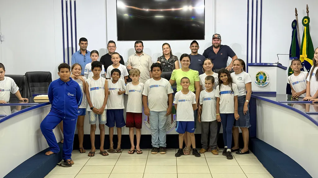Alunos da Escola Padre Anchieta, de camiseta branca do uniforme, posam com professoras e vereadores no plenário da Câmara Municipal de São José do Rio Claro